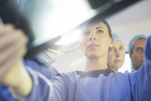 Chirurgen betrachten Röntgenbilder während einer Operation im Operationssaal - CAIF08434