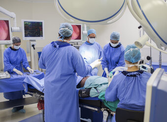 Team of doctors performing surgery in operating theater - CAIF08463