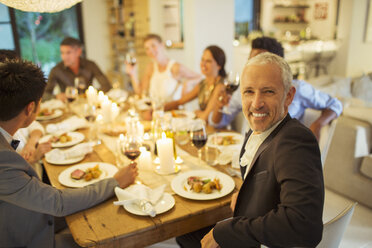 Man smiling at dinner party - CAIF08494