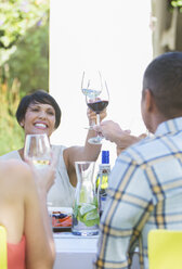 Friends toasting each other at table outdoors - CAIF08505