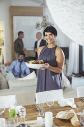 Woman serving food at dinner party - CAIF08514