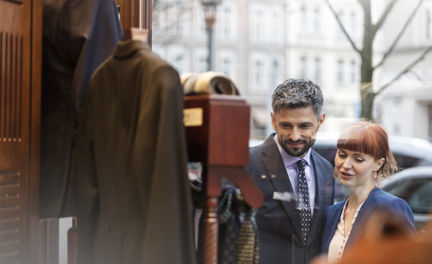 Paar beim Schaufensterbummel vor einem Herrenbekleidungsgeschäft, lizenzfreies Stockfoto