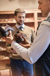 Businessman shopping for dress shoes in menswear shop - CAIF08579