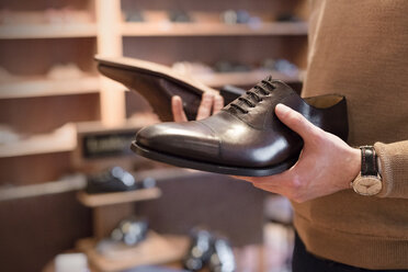 Businessman browsing dress shoes in menswear shop - CAIF08604