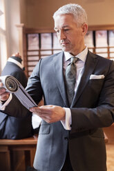 Businessman browsing fabric in menswear shop - CAIF08608