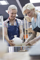 Frauen setzen Töpferwaren in den Brennofen im Atelier - CAIF08648