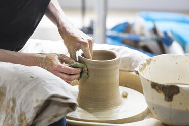 Woman using pottery wheel in studio - CAIF08652