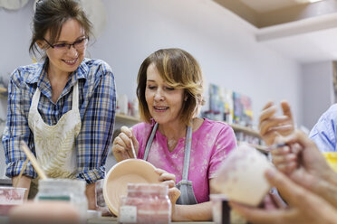 Ältere Frau, die in einem Atelier Töpferwaren bemalt - CAIF08653