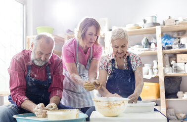 Lehrerin und älteres Ehepaar bei der Arbeit mit Töpferscheiben im Atelier - CAIF08662