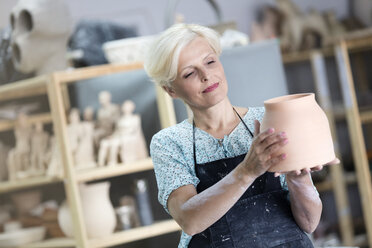 Ältere Frau hält Töpfervase im Atelier - CAIF08687