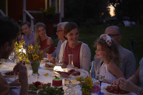Familie genießt Abendessen bei Kerzenlicht auf der Terrasse bei Nacht, lizenzfreies Stockfoto