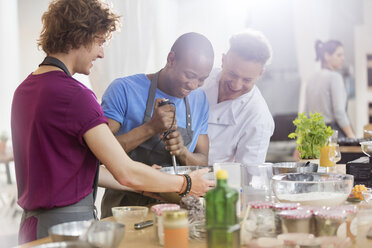 Kochlehrer und Schüler verwenden Handmixer in der Küche des Kochkurses - CAIF08749