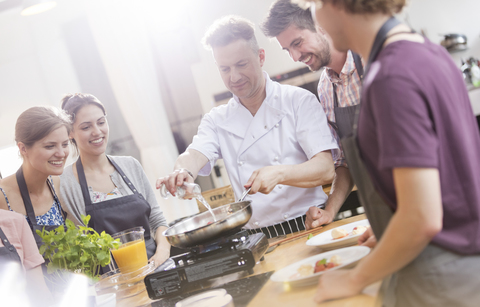 Schüler beobachten Kochlehrer in der Küche des Kochkurses, lizenzfreies Stockfoto