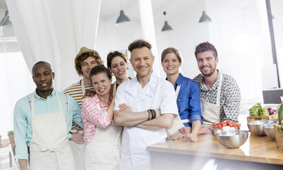 Portrait smiling chef teacher and students in cooking class kitchen - CAIF08766