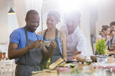 Mann fotografiert Essen in der Küche eines Kochkurses - CAIF08770