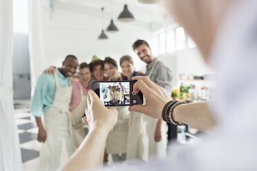Man photographing cooking class students in kitchen - CAIF08777