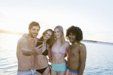 Junge erwachsene Freunde in Bikinis und Badehosen nehmen Selfie im Sommer Sonnenuntergang Meer - CAIF08780