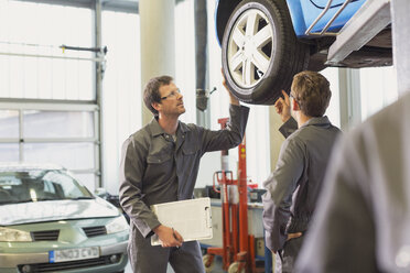 Mechaniker, die in einer Autowerkstatt Reifen untersuchen und besprechen - CAIF08792