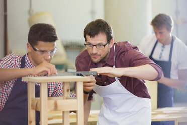 Focused carpenters measuring wood in workshop - CAIF08805