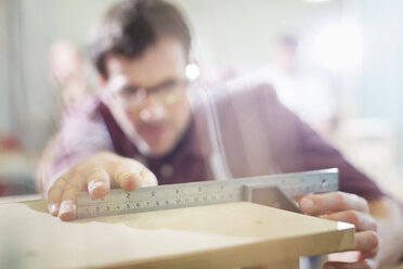 Carpenter measuring wood in workshop - CAIF08822