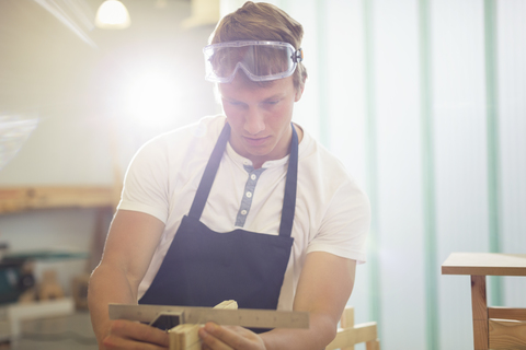 Tischler misst Holz mit Lineal in der Werkstatt, lizenzfreies Stockfoto