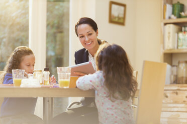 Arbeitende Mutter und Töchter am Frühstückstisch - CAIF08853