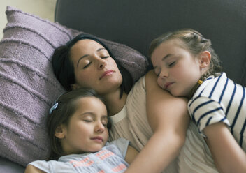 Serene mother and daughters napping on sofa - CAIF08857