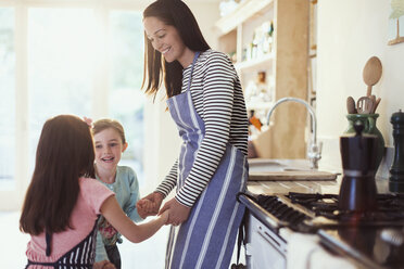 Mutter und Töchter halten sich in der Küche an den Händen - CAIF08877