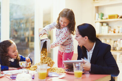 Mädchen gießt am Frühstückstisch reichlich Müsli ein - CAIF08879