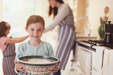 Porträt eines lächelnden Mädchens, das in der Küche eine Schüssel mit Mehl hält - CAIF08884