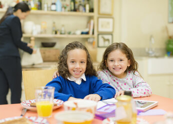 Portrait smiling sisters at breakfast table - CAIF08888