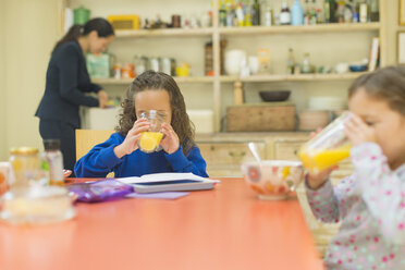 Mädchen trinken Orangensaft am Frühstückstisch - CAIF08892
