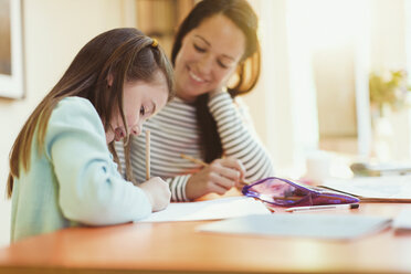 Mother watching daughter do homework - CAIF08898