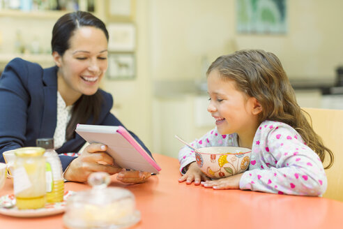 Mutter und Tochter benutzen ein digitales Tablet am Frühstückstisch - CAIF08906
