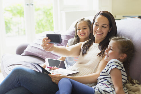 Mutter und Töchter machen ein Selfie auf dem Wohnzimmersofa - CAIF08911
