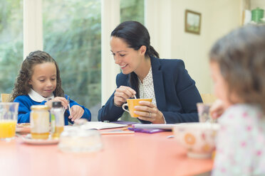 Arbeitende Mutter und Tochter bei den Hausaufgaben am Frühstückstisch - CAIF08918