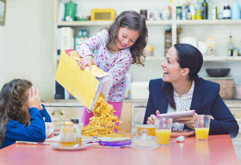 Verspieltes Mädchen schüttet reichlich Müsli auf den Frühstückstisch - CAIF08931