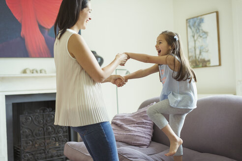 Verspielte Mutter und Tochter tanzen im Wohnzimmer - CAIF08939