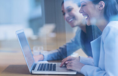 Lachende Geschäftsfrauen bei der Arbeit am Laptop - CAIF08945