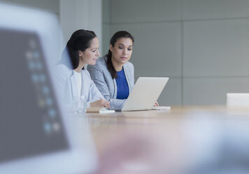 Geschäftsfrauen arbeiten an einem Laptop in einem Konferenzraum - CAIF08947