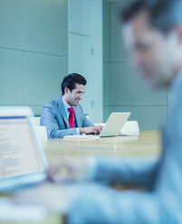 Businessman working at laptop in conference room - CAIF08954