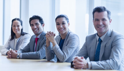 Porträt von lächelnden Geschäftsleuten, die in einer Reihe im Konferenzraum sitzen - CAIF08955