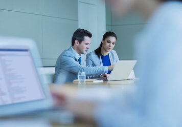 Geschäftsleute arbeiten an einem Laptop in einem Konferenzraum - CAIF08958