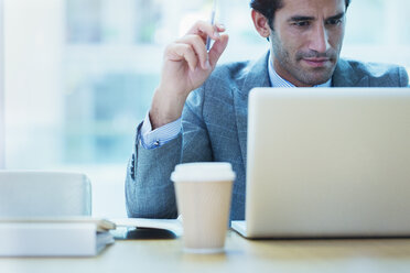 Konzentrierter Geschäftsmann bei der Arbeit am Laptop im Büro - CAIF08965