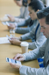 Geschäftsmann benutzt Mobiltelefon im Konferenzraum - CAIF08979