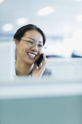 Lächelnde Geschäftsfrau beim Telefonieren im Büro - CAIF08983