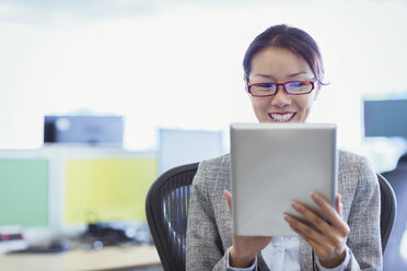Lächelnde Geschäftsfrau mit digitalem Tablet im Büro - CAIF08991