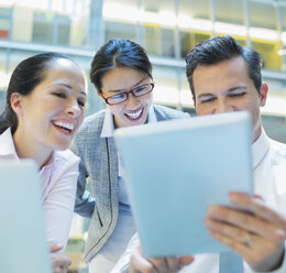 Lächelnde Geschäftsleute, die ein digitales Tablet im Büro benutzen - CAIF08998