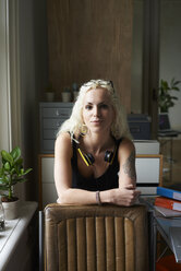 Porträt selbstbewusste junge Frau mit Kopfhörern und Tattoo im Heimbüro - CAIF09005