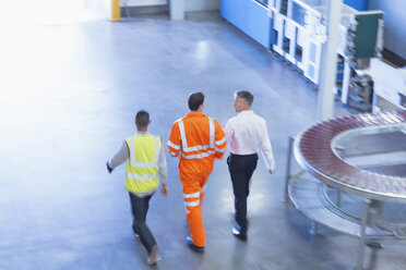 Arbeiter in reflektierender Kleidung gehen in einer Fabrik - CAIF09032